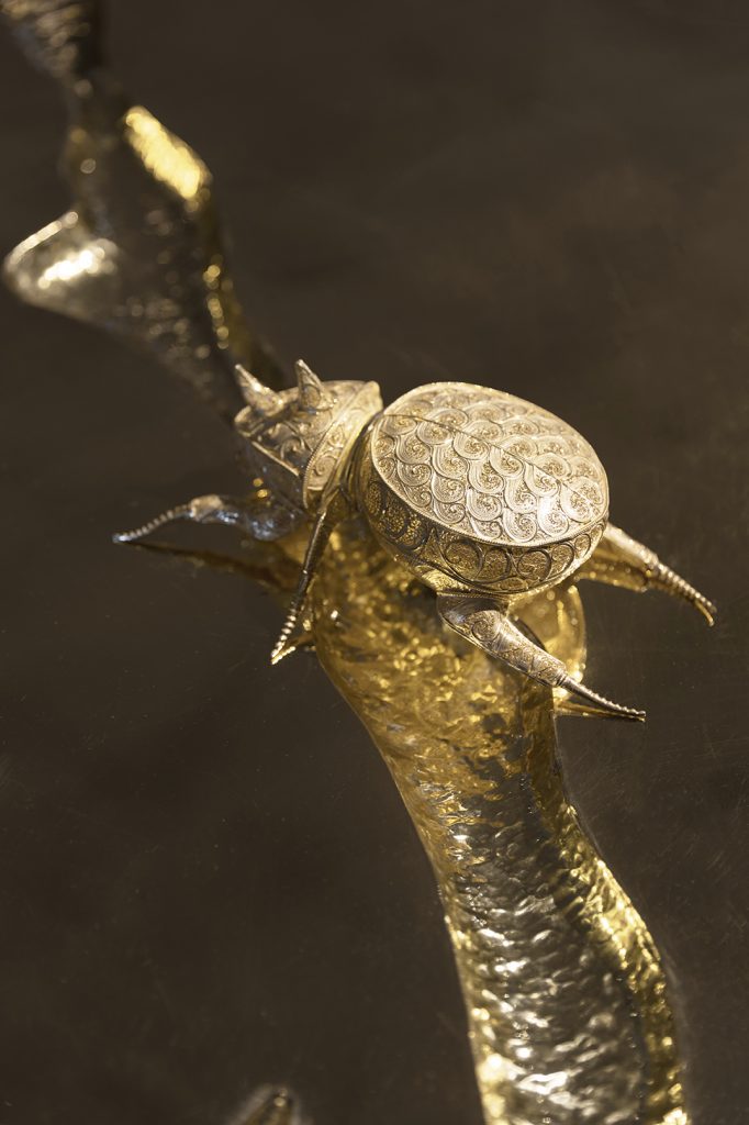 craftmanship - rhinocero in gold filigree  on top of a gold branch