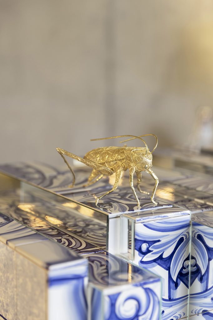 craftmanship - cricket in gold filigree  on top of a hand painted azulejo in blue and white
