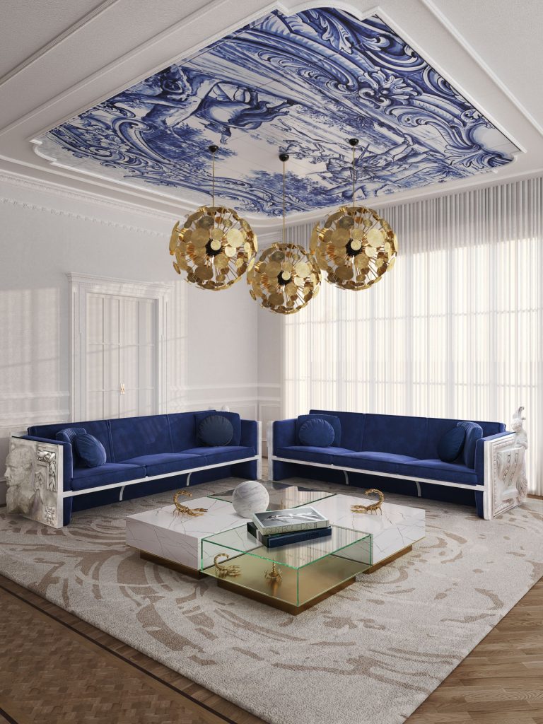 living room with two sofas in blue velvet fabric, three round golden pendant lamps and a transparent glass and white marble coffee table and a stone ceiling painted with blue tiles