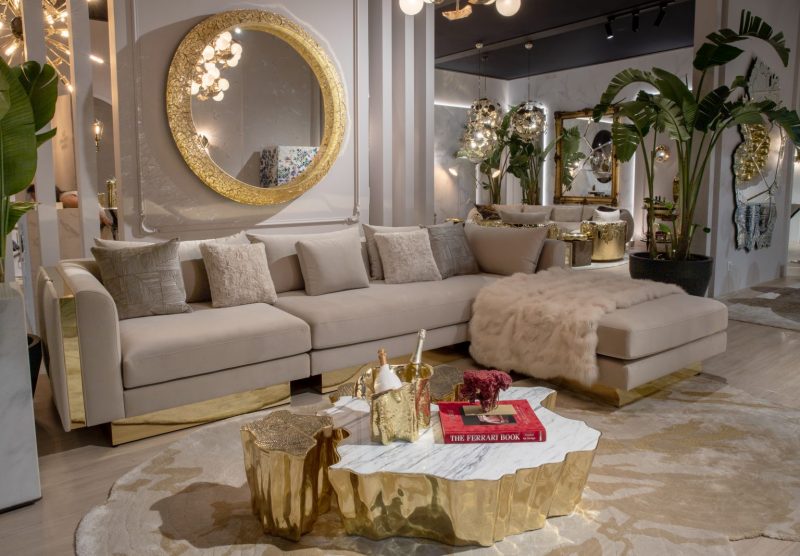 maximalism- contemporany living room with cream and gold sofa, brown rug, gold center table and plants